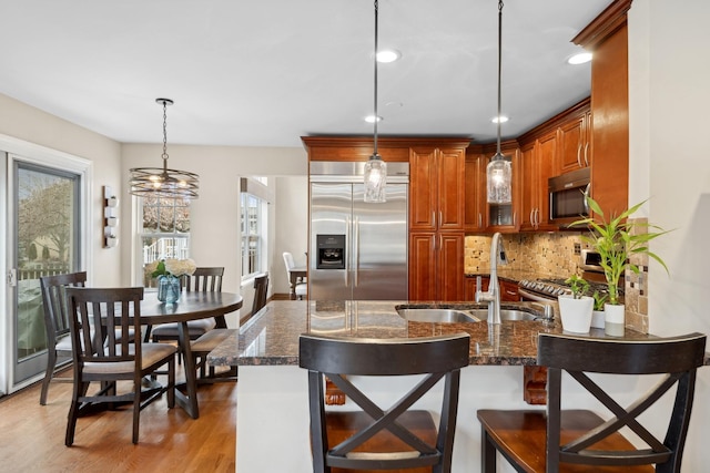 kitchen with decorative light fixtures, sink, dark stone countertops, and stainless steel appliances