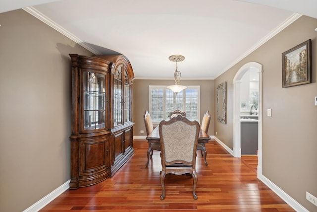 dining space with ornamental molding, wood-type flooring, and sink