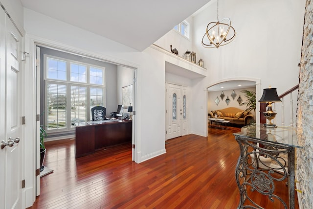 foyer entrance with a notable chandelier, hardwood / wood-style flooring, a healthy amount of sunlight, and a high ceiling