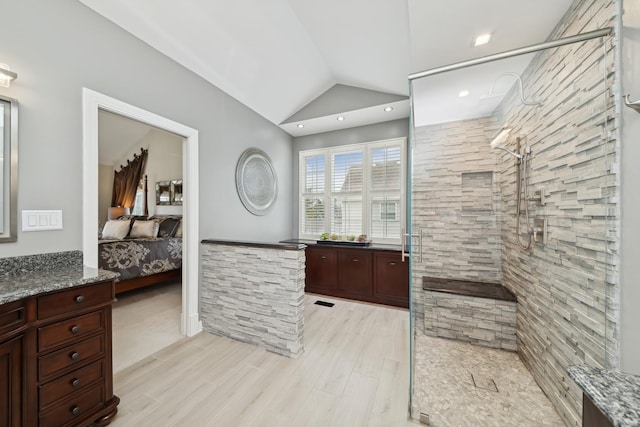 bathroom with hardwood / wood-style flooring, tiled shower, vanity, and vaulted ceiling