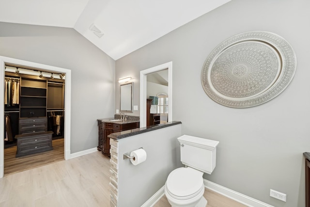 bathroom featuring lofted ceiling, vanity, hardwood / wood-style flooring, and toilet