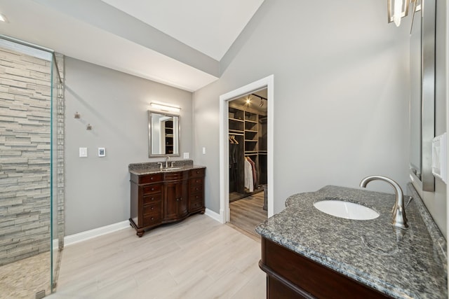 bathroom featuring hardwood / wood-style flooring, vanity, vaulted ceiling, and a shower