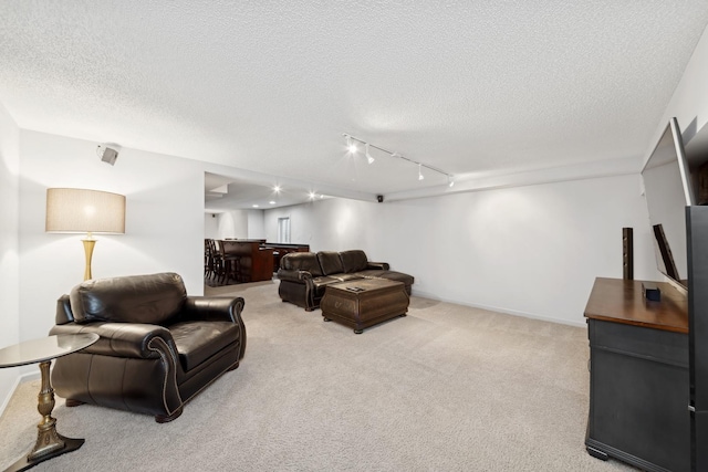 living room with light carpet, track lighting, a textured ceiling, and bar area