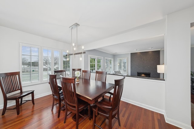 dining space featuring a large fireplace, a chandelier, and dark hardwood / wood-style floors