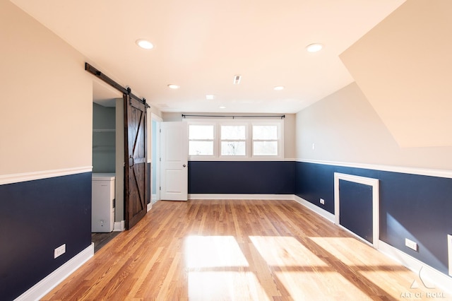 empty room featuring a barn door and light hardwood / wood-style flooring