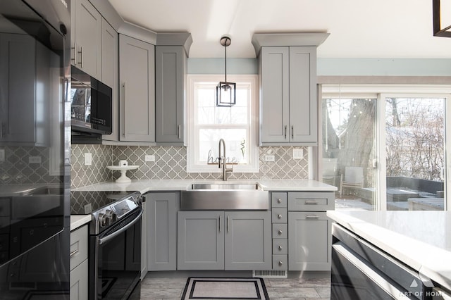 kitchen with gray cabinetry, pendant lighting, backsplash, sink, and appliances with stainless steel finishes