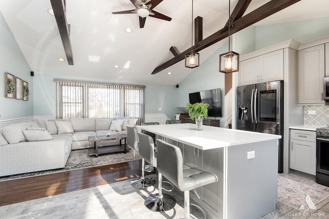 kitchen featuring backsplash, a breakfast bar, lofted ceiling with beams, decorative light fixtures, and a center island