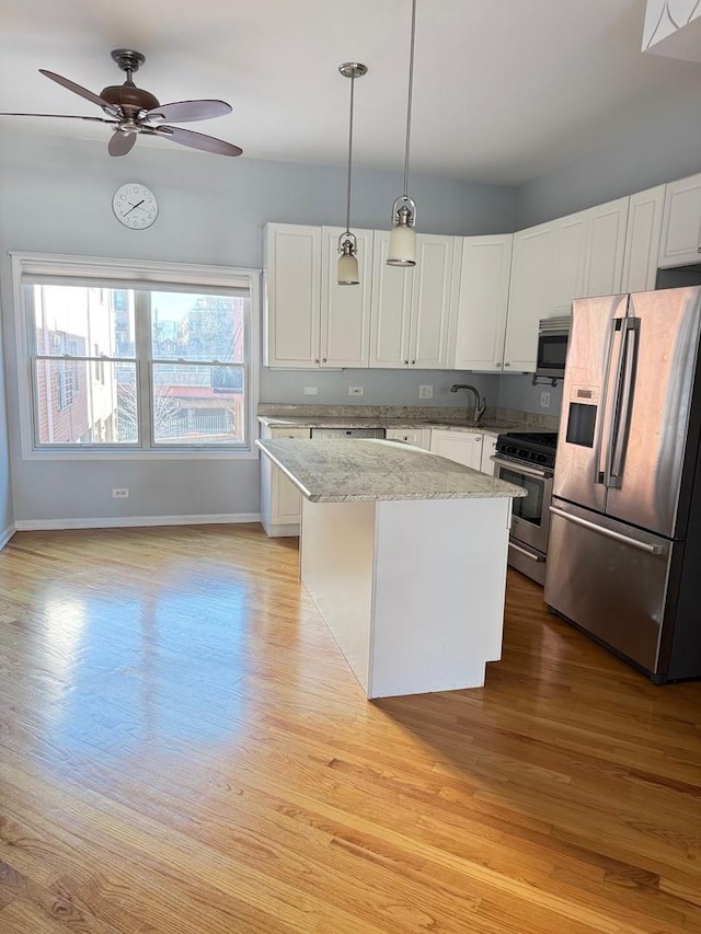 kitchen with pendant lighting, appliances with stainless steel finishes, a center island, and white cabinets