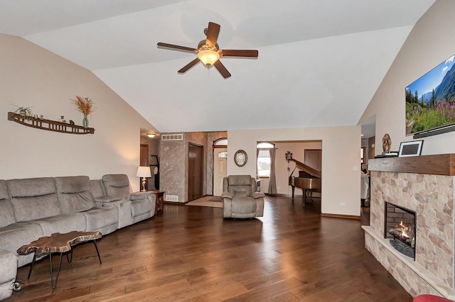 living room with ceiling fan, a stone fireplace, dark hardwood / wood-style flooring, and vaulted ceiling