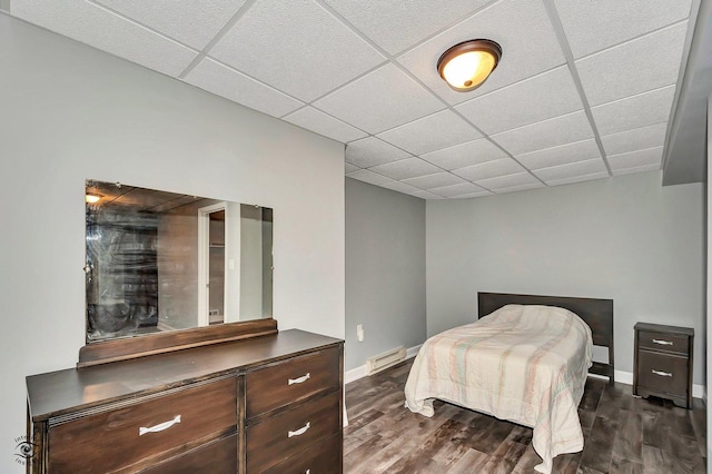 bedroom featuring dark hardwood / wood-style floors, a drop ceiling, and a baseboard heating unit