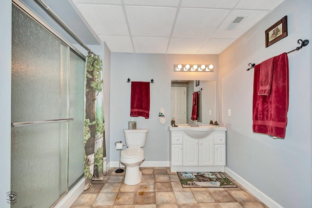 bathroom with a drop ceiling, vanity, an enclosed shower, and toilet