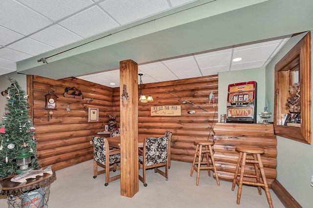 dining room featuring a paneled ceiling, log walls, and indoor bar