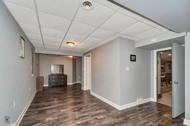 interior space with a paneled ceiling and dark hardwood / wood-style floors