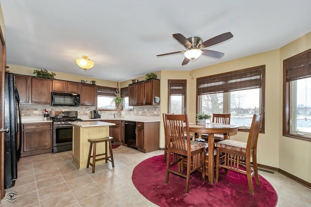 kitchen featuring ceiling fan, a kitchen island, tasteful backsplash, light tile patterned flooring, and black appliances