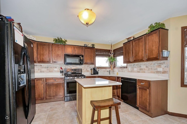 kitchen featuring light tile patterned flooring, black appliances, a kitchen breakfast bar, sink, and a kitchen island