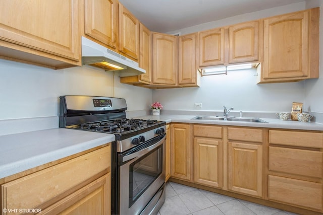 kitchen with light brown cabinetry, sink, light tile patterned floors, and stainless steel range with gas stovetop