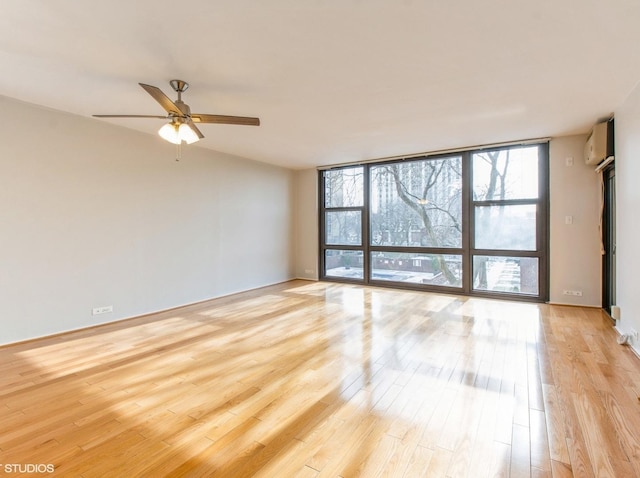 spare room with ceiling fan, floor to ceiling windows, light hardwood / wood-style floors, and a wall unit AC