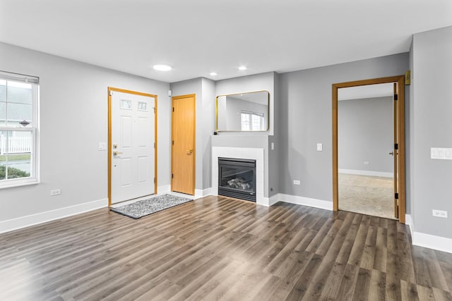 unfurnished living room with dark hardwood / wood-style floors and a tiled fireplace