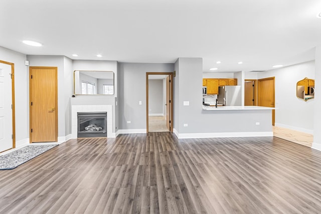 unfurnished living room featuring hardwood / wood-style flooring and a tiled fireplace