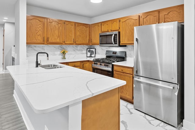 kitchen with kitchen peninsula, decorative backsplash, sink, and appliances with stainless steel finishes