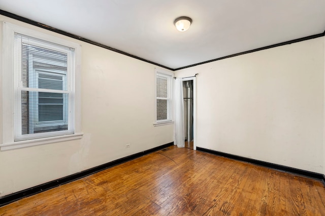 unfurnished room with a healthy amount of sunlight, ornamental molding, and wood-type flooring