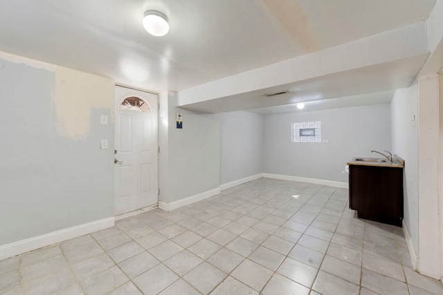 basement with light tile patterned flooring and sink