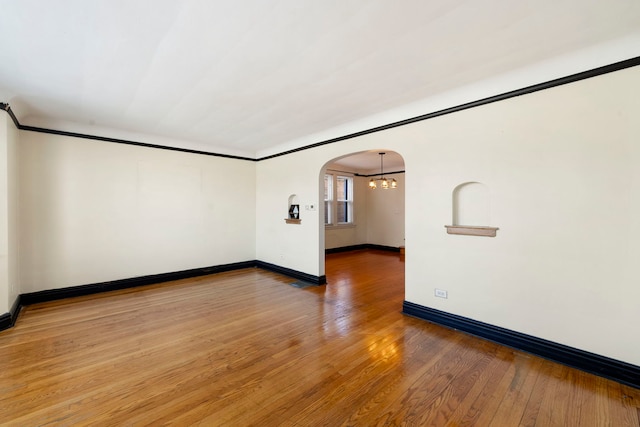 spare room featuring hardwood / wood-style floors and a notable chandelier