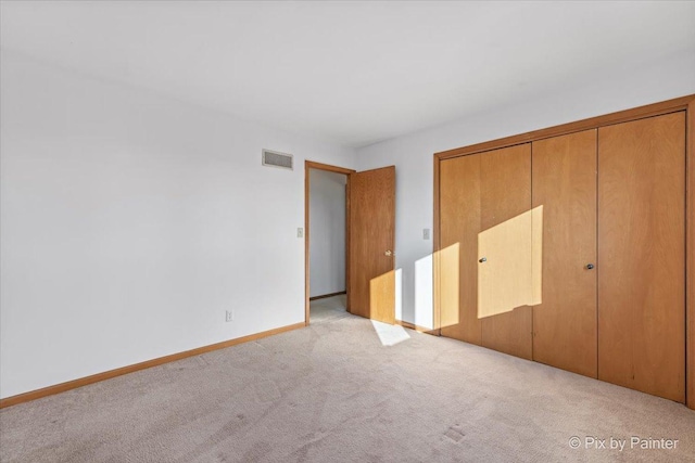 unfurnished bedroom with light carpet and a closet