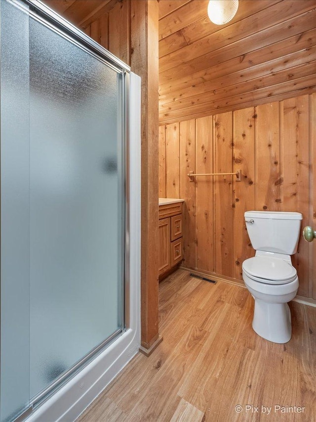 bathroom with wood walls, hardwood / wood-style flooring, toilet, an enclosed shower, and wood ceiling