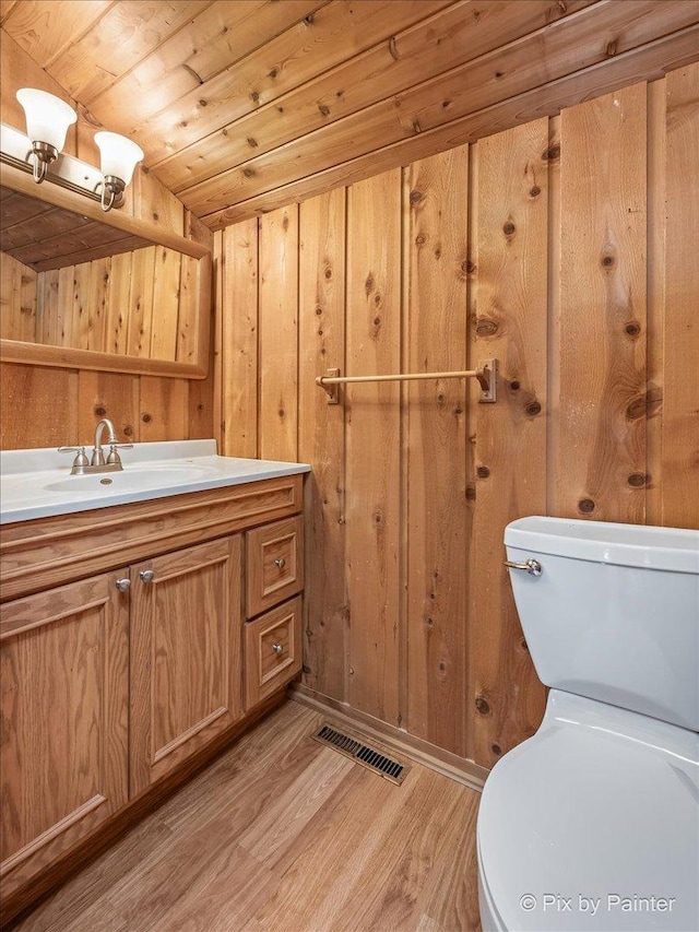 bathroom with hardwood / wood-style floors, wood walls, vaulted ceiling, toilet, and wood ceiling