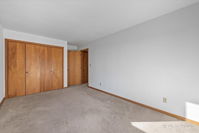 unfurnished bedroom featuring light colored carpet and a closet