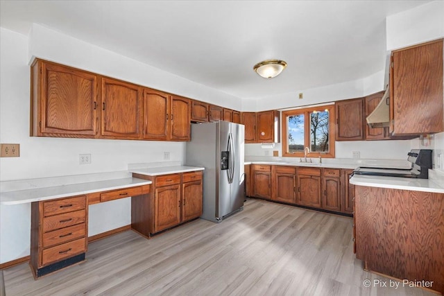 kitchen featuring sink, range, stainless steel refrigerator with ice dispenser, exhaust hood, and light wood-type flooring