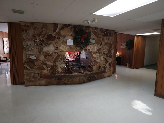 basement featuring a drop ceiling and wood walls