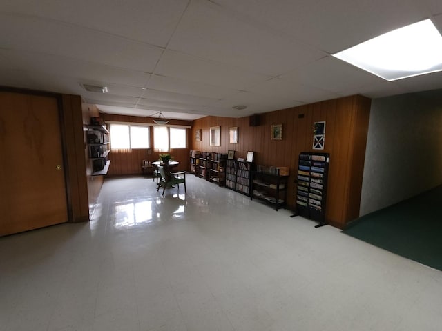 basement with wood walls and a drop ceiling