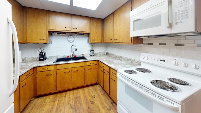 kitchen featuring sink, a drop ceiling, backsplash, white appliances, and light wood-type flooring