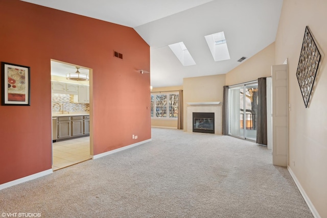 unfurnished living room with light carpet, sink, and vaulted ceiling with skylight