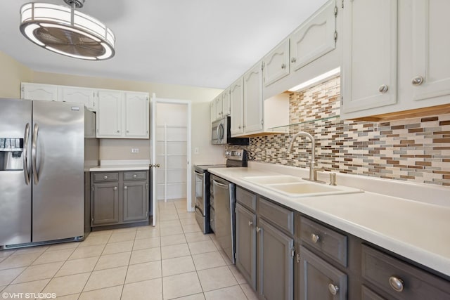 kitchen with backsplash, sink, light tile patterned floors, white cabinetry, and stainless steel appliances