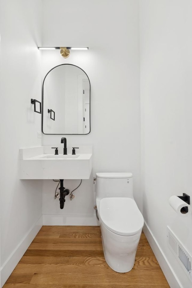 bathroom with hardwood / wood-style flooring and toilet