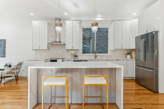 kitchen featuring white cabinetry, a center island, sink, stainless steel fridge, and pendant lighting