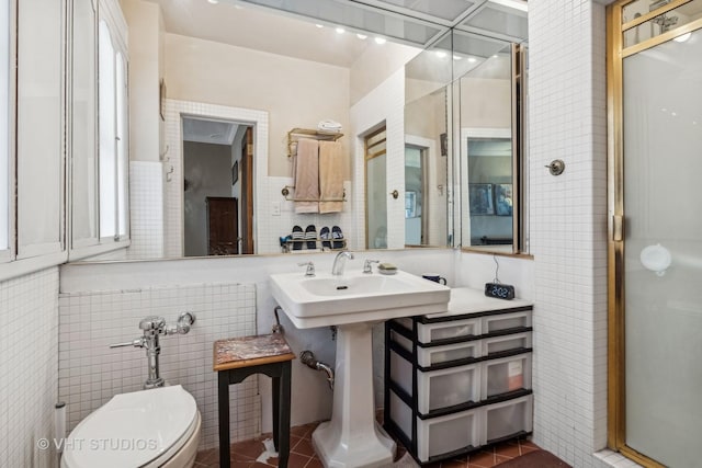 bathroom with toilet, a shower, tile patterned floors, and tile walls