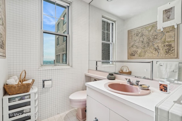 bathroom featuring tile patterned floors, vanity, tile walls, and toilet