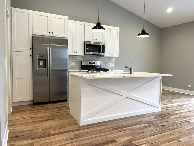 kitchen featuring appliances with stainless steel finishes, tasteful backsplash, hardwood / wood-style flooring, a center island with sink, and white cabinetry