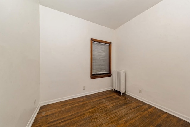 unfurnished room featuring radiator and dark hardwood / wood-style floors