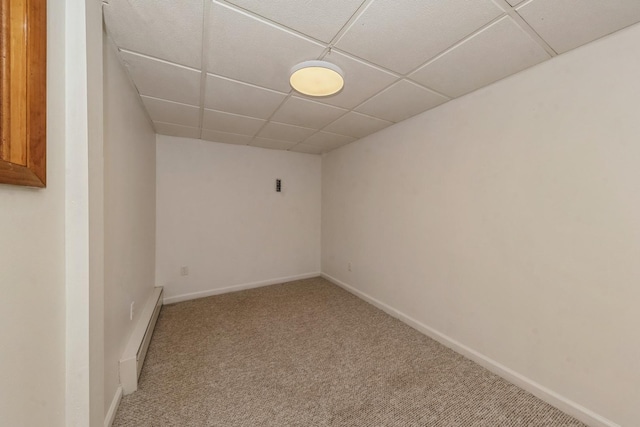 carpeted empty room featuring baseboard heating and a drop ceiling