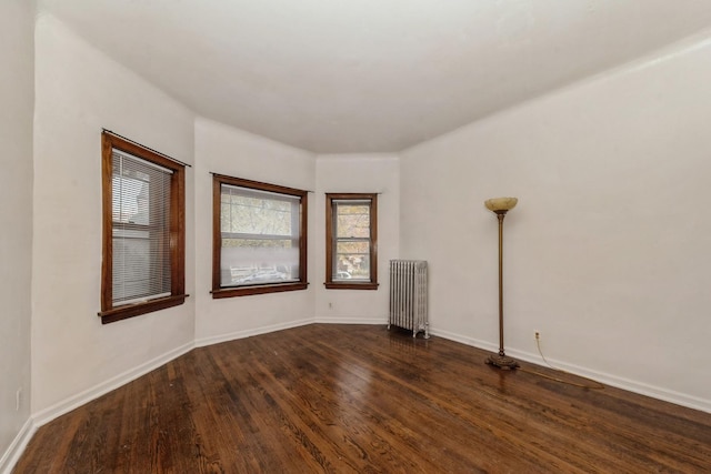 spare room featuring radiator heating unit and dark wood-type flooring