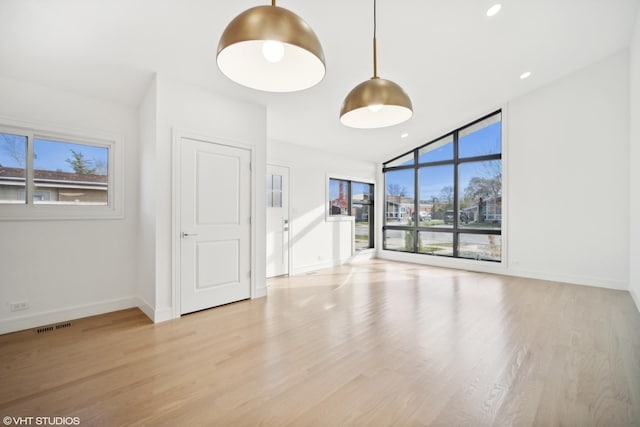 unfurnished living room featuring plenty of natural light and light wood-type flooring