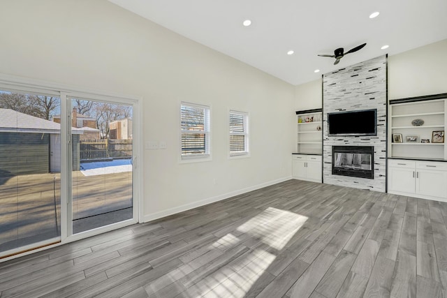 unfurnished living room with ceiling fan, light hardwood / wood-style floors, a wealth of natural light, and a tile fireplace