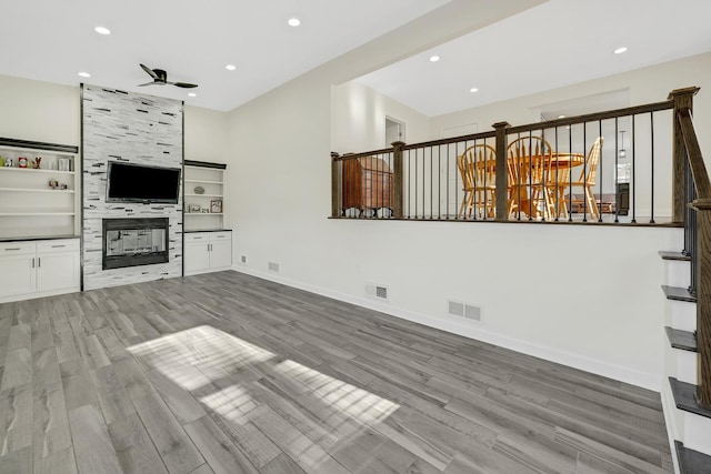 unfurnished living room featuring light hardwood / wood-style flooring, ceiling fan, and a tiled fireplace