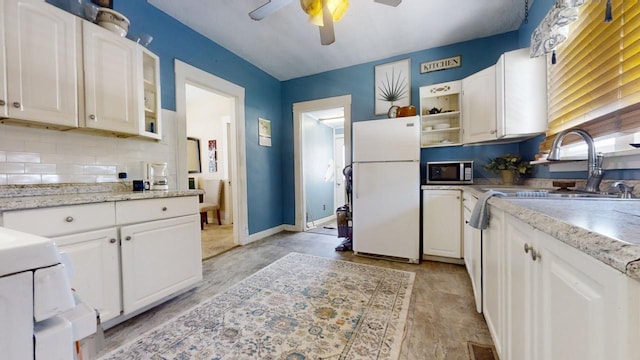 kitchen featuring sink, white cabinetry, white fridge, ceiling fan, and decorative backsplash