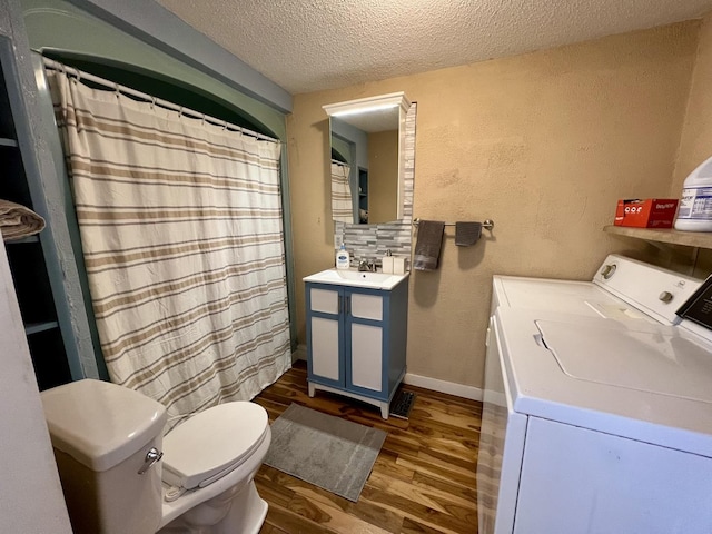 bathroom featuring independent washer and dryer, toilet, wood-type flooring, vanity, and a textured ceiling